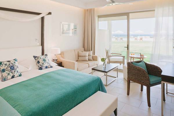 Schlafzimmer im Candia Maris Resort & Spa mit Bett, Couch, Tisch und Meerblick.
