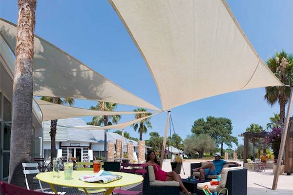 Hotelterrasse mit Sonnenschirm und Sofas, wo Gäste sich entspannen.