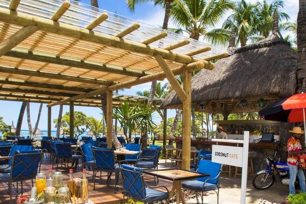 Coconut Cafe im La Pirogue Mauritius Hotel mit blauen Stühlen und Tischen unter einem Pavillon.