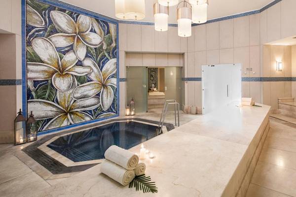 Wellnessbereich im La Pirogue Mauritius Hotel mit Swimmingpool, Kerzen und blauen Wandfliesen.
