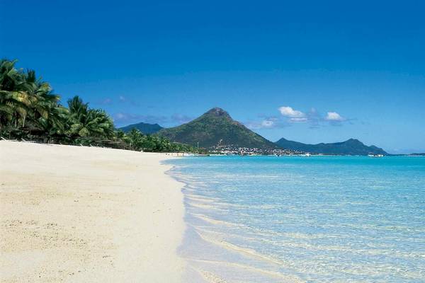 Strand am La Pirogue Mauritius Hotel mit weißen Sand, blauem Wasser und Bergen im Hintergrund
