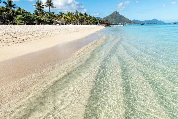Strandszenerie mit klarem Wasser und weißem Sand am La Pirogue Mauritius Hotel