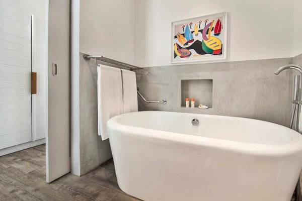 Das Badezimmer des La Pirogue Mauritius Hotels mit Badewanne, Handtuchhalter und Gemälde an der Wand.