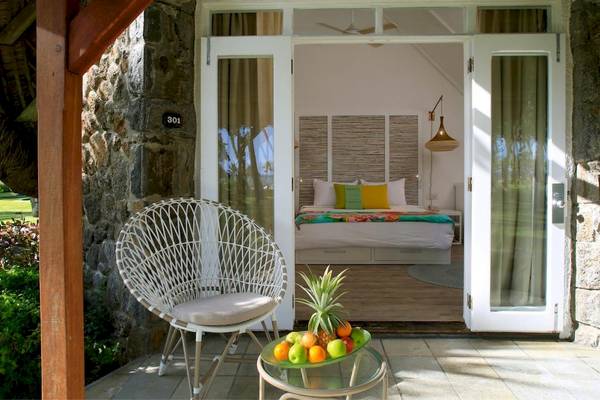 Innenansicht eines Zimmers im Hotel La Pirogue Mauritius mit einem Bett, Obst und einem offenen Balkon.