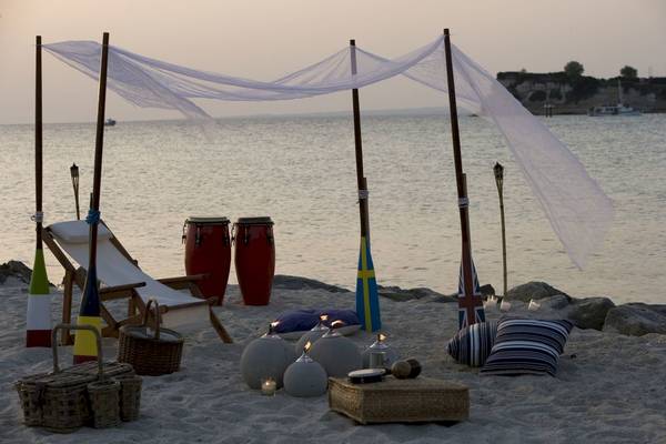 Strandaufstellung des Sani Clubs mit Strandstuhl, Trommeln und Laternen am Wasser