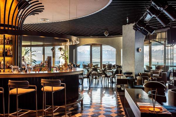 Innenansicht der Bar im Akra Hotel mit moderner Einrichtung und Blick auf das Meer.