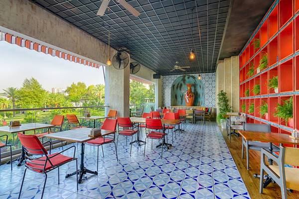 Innenbereich des Akra Hotels mit geometrisch gefliestem Boden, rot und blau gestreiften Tischdecken und roten Stühlen.