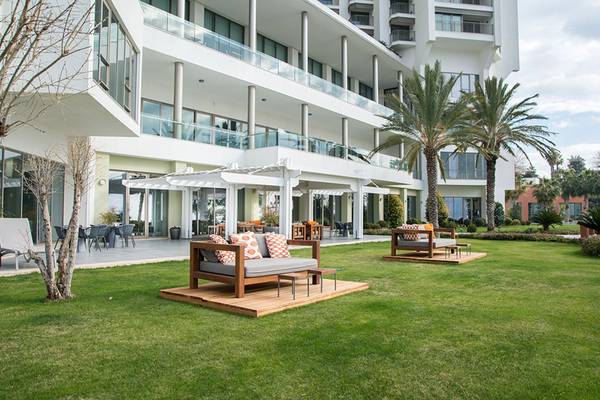 Außenbereich des Akra Hotels mit modernen Sofas und Palmen im Vordergrund.
