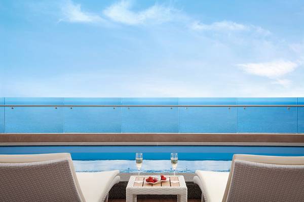 Terrasse des Akra Hotels mit Blick auf das Meer und zwei Champagnergläsern mit Erdbeeren.