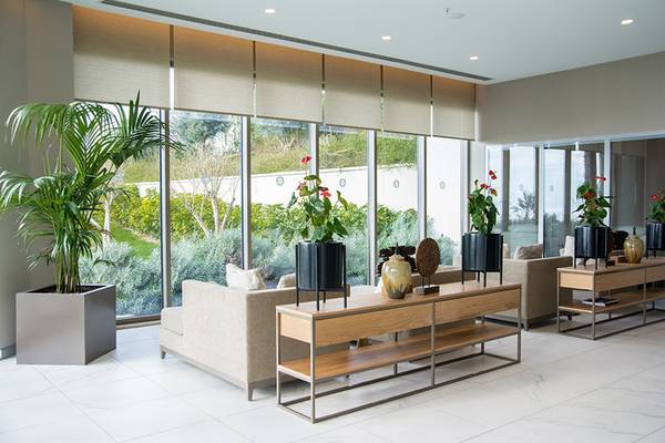 Lobby-Bereich des Akra Hotels mit Sofas, Tischen, Blumen und großen Fenstern.