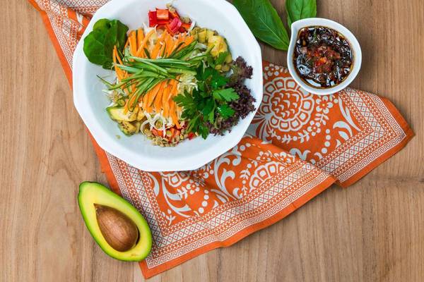 Teller mit Gemüsesalat und Avocado auf einem orangefarbenen Tuch