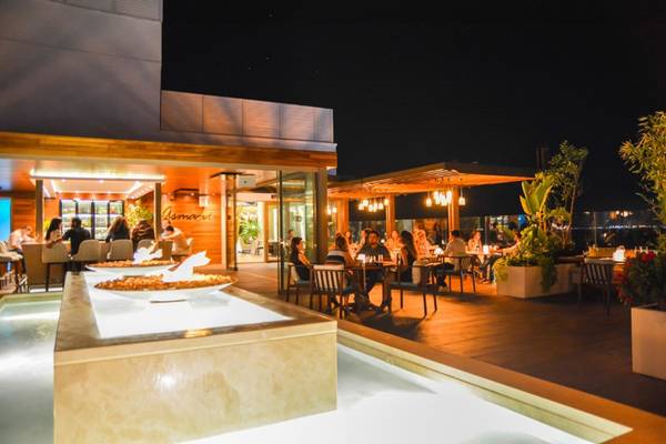 Akra Hotel Außenbereich bei Nacht mit Gästen an Tischen unter Überdachungen