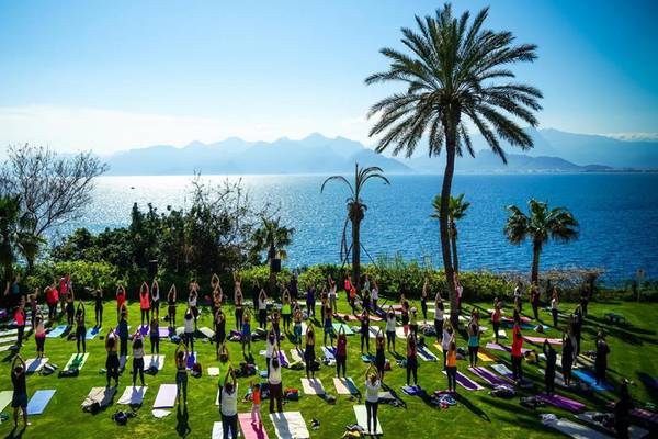 Ein Yoga-Kurs im Freien, mit Blick auf das Meer und die Berge, im Akra Hotel.