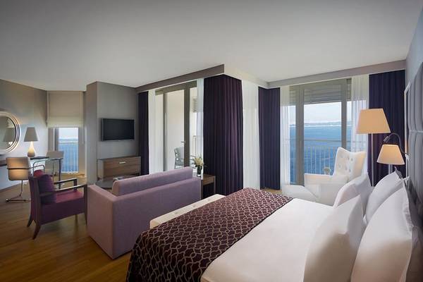 Suite im Akra Hotel mit Meerblick, inklusive Bett, Sofa, Fernseher und Balkon.
