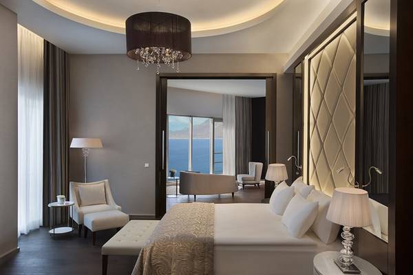 Schlafzimmer im Akra Hotel mit Blick auf das Meer, modernes Design, großem Bett und eleganten Möbeln.