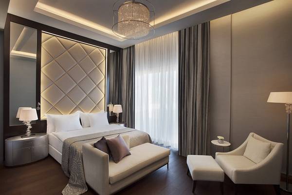 Schlafzimmer im Akra Hotel mit einem Bett, einer Couch, Stühlen und Lampen.