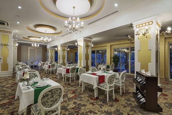 Innenbereich des Crystal Tat Beach Golf Resort & Spa mit einem eleganten Restaurant, komplett eingerichtet mit Tischen, Stühlen und Kronleuchtern.