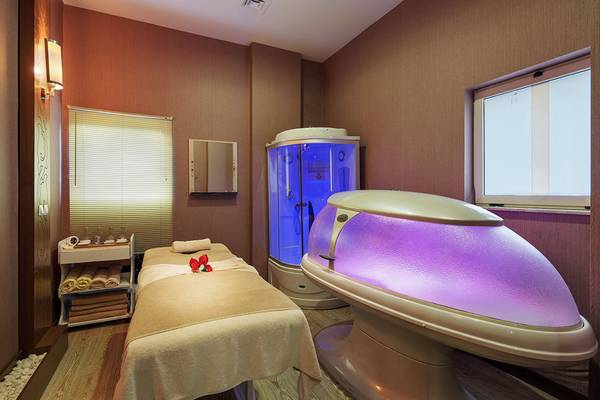Spa-Behandlungsraum im Kristall Tat Strand Golf Resort & Spa mit einer Massageliege, einer Sauna und einem violetten Lichtgerät.
