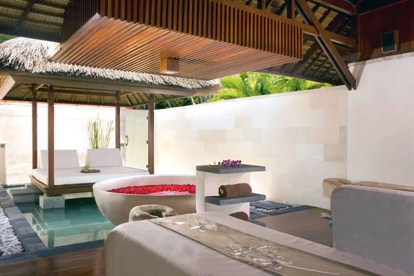 Innenbereich des Nusa Dua Beach Hotel & Spa mit einem großen Rosenblütenbad und Liegestühlen.