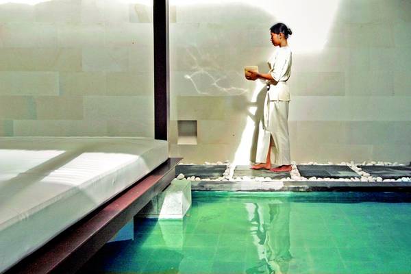 Eine Person in weißer Kleidung steht am Pool im Zimmer des Nusa Dua Beach Hotel & Spa.