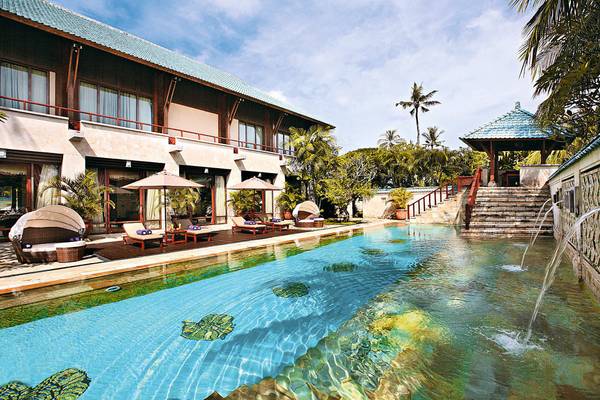 Außenpoolbereich des Nusa Dua Beach Hotel & Spa mit Liegestühlen und Sonnenschirmen.