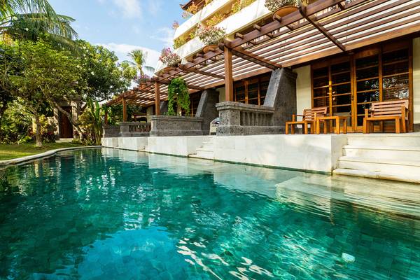 Außenpool des Nusa Dua Beach Hotel & Spa mit umgebender Terrasse und Holzmöbeln