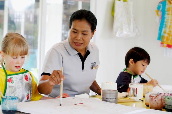Eine Frau und zwei Kinder malen in einem Raum des Dusit Thani Laguna Phuket.