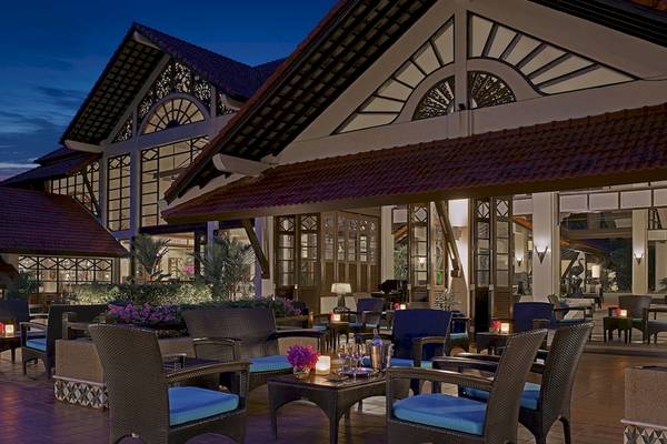 Außenbereich des Dusit Thani Laguna Phuket Hotels bei Nacht mit beleuchteten Tischen und Stühlen.