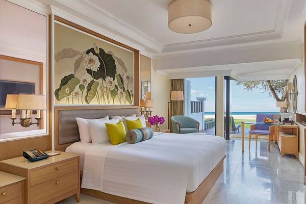 Innenansicht eines Zimmers im Dusit Thani Laguna Phuket mit großem Bett, Blick auf den Ozean und modernem Interieur.
