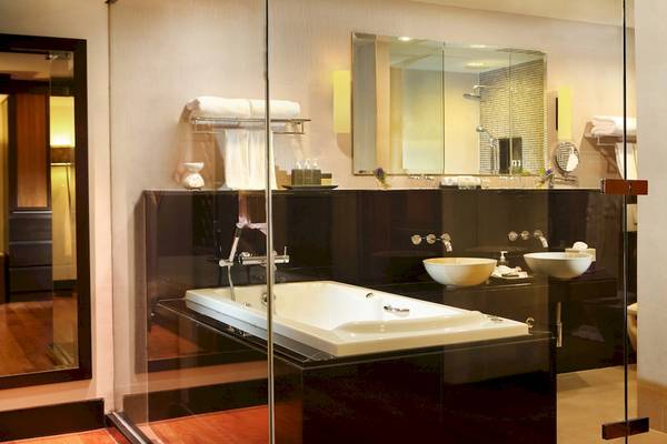 Badezimmer im Dusit Thani Laguna Phuket mit Badewanne, Waschbecken und Spiegel.