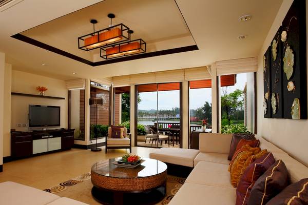Wohnzimmer im Dusit Thani Laguna Phuket mit großem Sofa, Tisch und Fernseher.