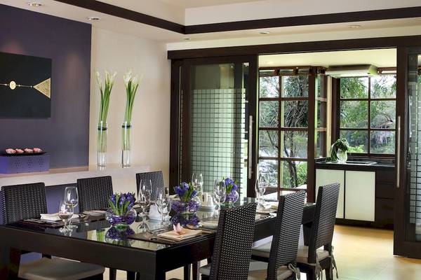 Das Speisezimmer im Dusit Thani Laguna Phuket mit Tisch, Stühlen und Fenstern.