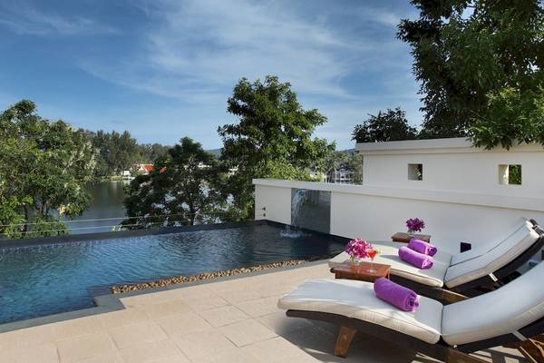 Terrasse des Dusit Thani Laguna Phuket mit Swimmingpool und Liegen mit Blick auf den See.