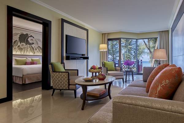 Wohnzimmer des Dusit Thani Laguna Phuket Hotels mit Sofa, Tisch und Fernseher.
