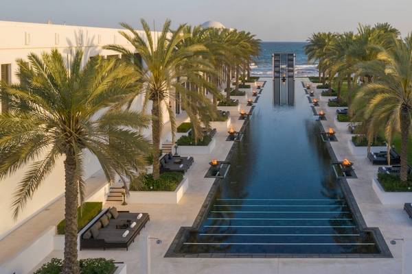 Außenansicht des Chedi Muscat Hotels mit einem langen Pool und Palmen