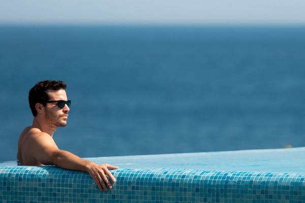 Mann, der am Rand des Infinity-Pools von Xanadu Island Bodrum steht und auf das Meer blickt.