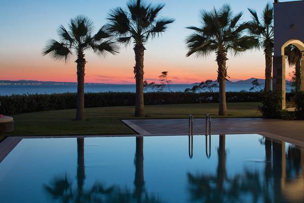 Sonnenuntergang am Xanadu Island Bodrum mit Swimmingpool und Palmen im Vordergrund.