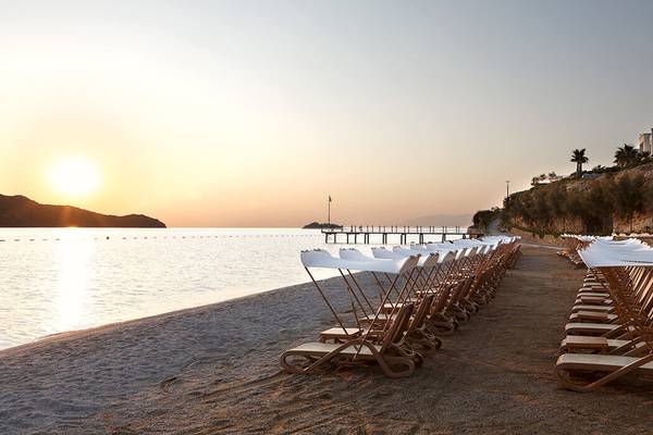 Sonnenuntergang am Xanadu Island Bodrum Strand mit Sonnenliegen in Reihe