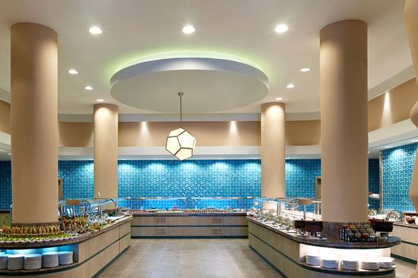 Innenansicht des Restaurants im Xanadu Island Bodrum Hotel mit blauen Wänden und mehreren Buffets.