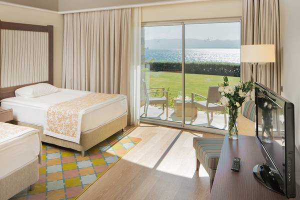 Hotelzimmer von Xanadu Island Bodrum mit zwei Betten und Meerblick durch große Glastüren.