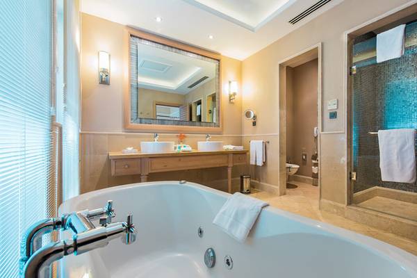 Luxuriöses Badezimmer im Xanadu Island Bodrum Hotel mit Badewanne, Spiegel, Waschbecken und Dusche.