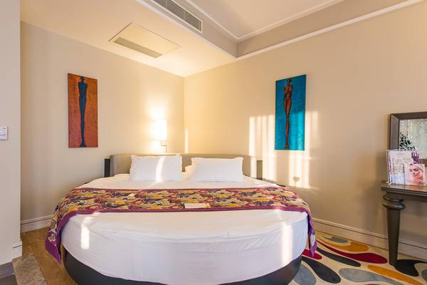 Schlafzimmer im Xanadu Island Bodrum Hotel mit rundem Bett, zwei weißen Kissen und zwei Gemälden an der Wand.