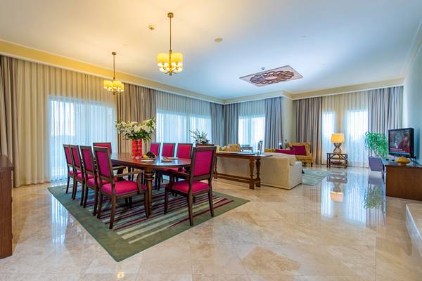 Wohnzimmer-Innenansicht des Xanadu Island Bodrum Hotels mit Esstisch, Sesseln und Couchgarnitur.