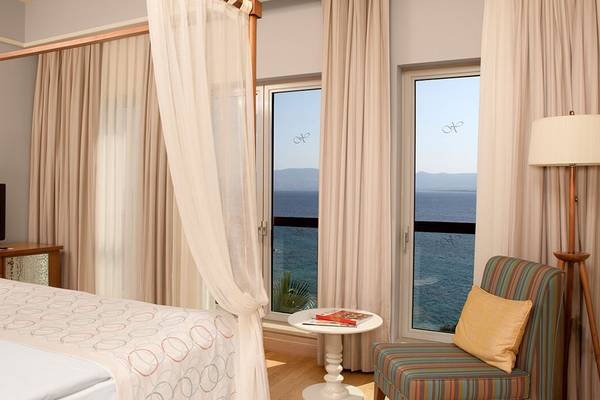 Hotelzimmer mit Meerblick im Xanadu Island Bodrum, mit Baldachinbett, Tisch und Meersichtfenstern.