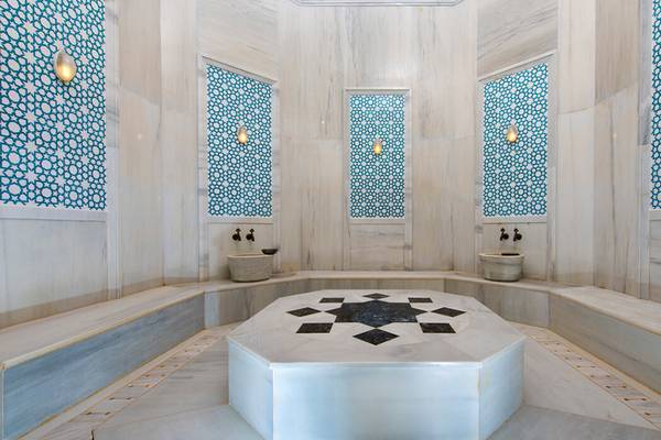 Innenansicht des Hammams im Xanadu Island Bodrum Hotel mit weißen Marmorwänden und blauen Wandmustern.