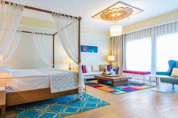 Schlafzimmer im Xanadu Island Bodrum Hotel mit Himmelbett, buntem Teppich und Wohnzimmerbereich