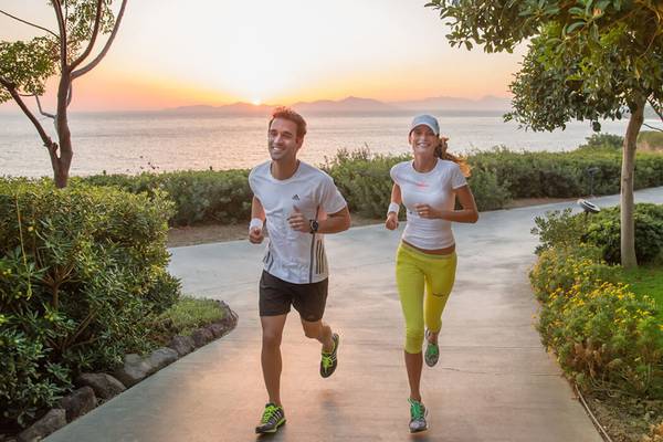 Zwei Menschen joggen auf einem Weg am Strand bei Sonnenuntergang im Xanadu Island Bodrum.