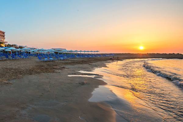 Sonnenuntergang am Strand des Themis Beach Hotels mit vielen Liegen und Sonnenschirmen