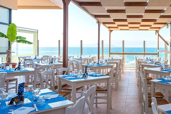 Das Außenrestaurant des Themis Beach Hotels mit Blick auf das Meer und gedeckten Tischen.