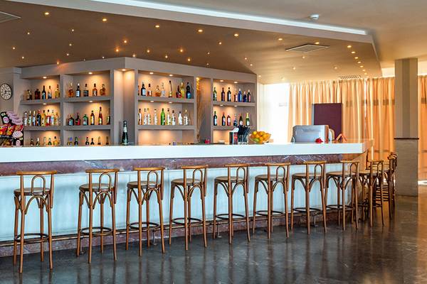 Barbereich im Themis Beach Hotel mit vielen Flaschen und Stühlen.